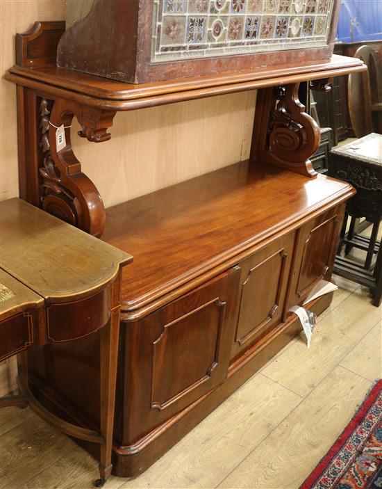 A Victorian mahogany buffet, with panel and shelf above, on openwork S scroll supports, with three panelled doors W.137cm